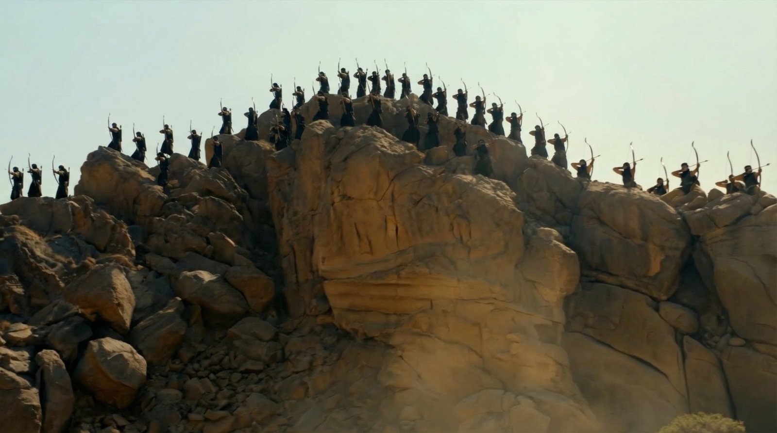 A line of archers arranged across a rocky ridge in a historical reconstruction